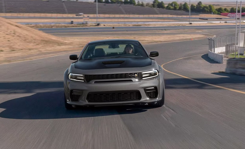 A gray 2023 Dodge Charger Scat Pack taking a curve on a track at a racing complex. 